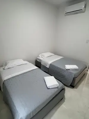 two beds in a white room with towels on them at Villa Sabanilla Casa bifamiliar campestre con piscina privada Aire acondicionado Tranquilidad total in Puerto Colombia