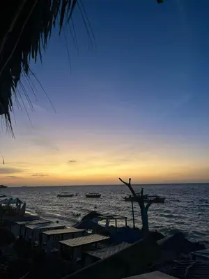 a sunset on the beach with boats in the water at Coco Cabaña Barú in Cartagena de Indias