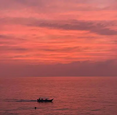 a boat in the middle of the ocean with a sunset at Coco Cabaña Barú in Cartagena de Indias
