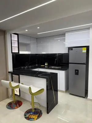 a kitchen with a black counter and two yellow chairs at Apartamento exclusivo y nuevo en el norte de Barranquilla in Barranquilla