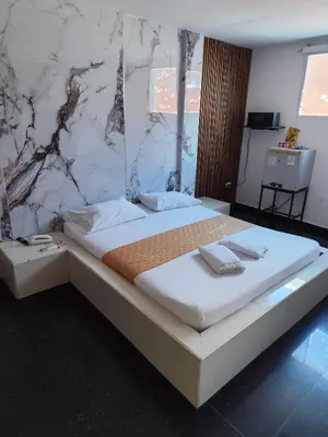 a large bed in a bedroom with a marble wall at Hotel El Tesoro in Barranquilla