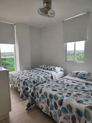 two beds in a room with two windows at Apto Coveñas in Coveñas
