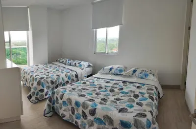 two beds in a room with two windows at Apto Coveñas in Coveñas