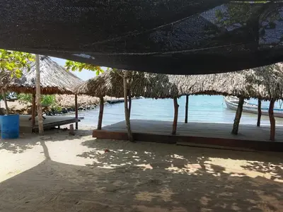 a beach with a bench and straw umbrellas and the water at Hotel Pesquera rincon berrugas in Berrugas