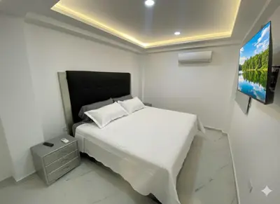 a bedroom with a white bed and a flat screen tv at Apto de 3 habitaciones cerca del areopuerto de CTG in Cartagena de Indias
