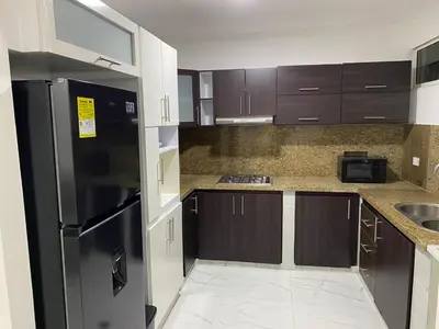 a kitchen with brown cabinets and a black refrigerator at Apto de 3 habitaciones cerca del areopuerto de CTG in Cartagena de Indias