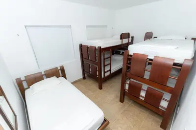 a room with three beds and a table and chairs at Country cabin, Coveñas in Coveñas