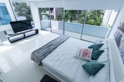 a white bedroom with a bed with pillows and a television at Luxury House Cartagena Private pool in Cartagena de Indias