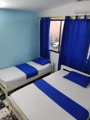 two beds in a room with a window at Hotel Palma Azul in Coveñitas