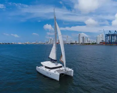 a sail boat in the water with a city in the background at 10BR Mansion Beachfront w Pool and Disco in Cartagena de Indias