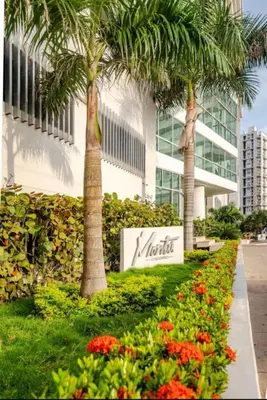 a sign in front of a building with palm trees and flowers at Apartamento a pasos del mar y centro en Cartagena, piscina sauna & turco in Cartagena de Indias