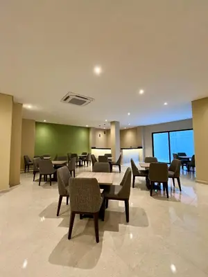 a lobby with tables and chairs and a green wall at BQ84 Urban Hotel in Barranquilla