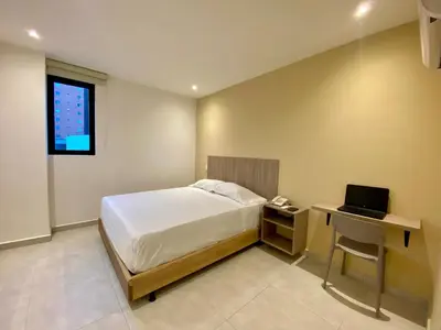 a bedroom with a bed and a desk with a laptop at BQ84 Urban Hotel in Barranquilla