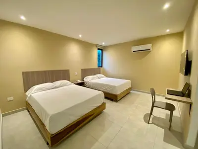 a bedroom with two beds and a desk and a chair at BQ84 Urban Hotel in Barranquilla