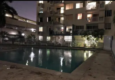 a swimming pool in front of a building at night at Cómoda habitación cerca de la via 40 Carnaval Barranquilla in Barranquilla