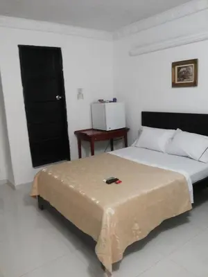 a bedroom with a bed with a black door and a table at hotel hispanoamericano in Barranquilla