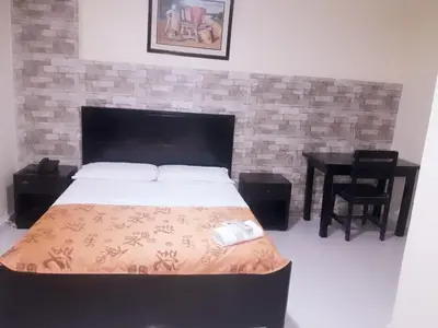 a bedroom with a large bed and a table at hotel hispanoamericano in Barranquilla