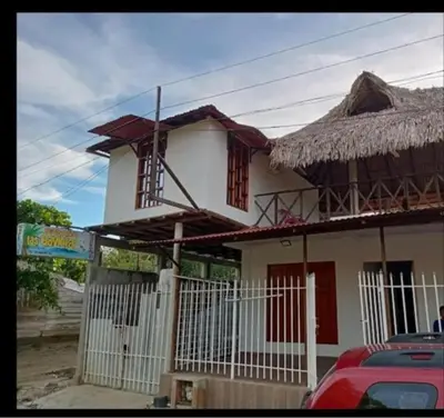 a small white house with a thatch roof at Cabaña y Hospedaje Las Gaviotas in Moñitos