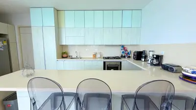 a kitchen with a counter with four chairs in it at Magico Apartamento Frente al Mar 5 Habitaciones OS121 in Coveñitas