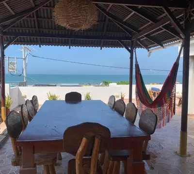 a table and chairs under an umbrella with the ocean at Hostel - La Catalina PLus in Cartagena de Indias