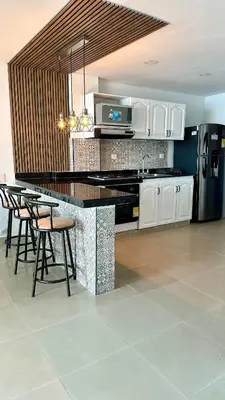a kitchen with a counter with chairs and a refrigerator at Vive al estilo Cartagenero frente al mar y al lago in Cartagena de Indias