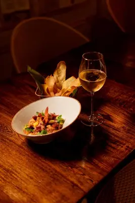 a plate of food and a glass of wine on a table at Cuna 58 in Barranquilla