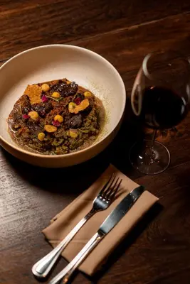 a bowl of food on a table next to a glass of wine at Cuna 58 in Barranquilla