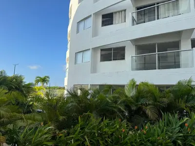 a tall white building with palm trees in front of it at Apartamento Serena del mar Trevi in Cartagena de Indias