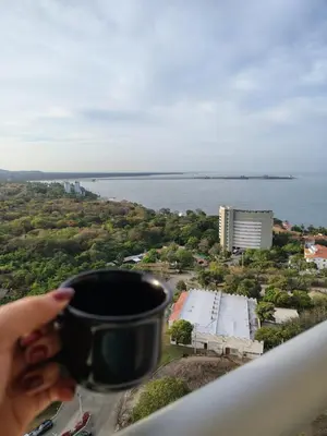 a person holding a cup of coffee on top of a building at Apartamento de lujo en Santa Marta in Santa Marta