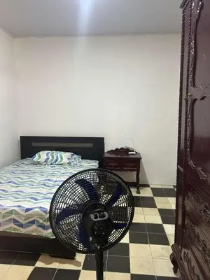 a room with a fan on the floor next to a bed at Habitacion con baño en zona de carnaval in Barranquilla