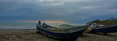 two boats sitting on the shore of a beach at El Castillo in Moñitos