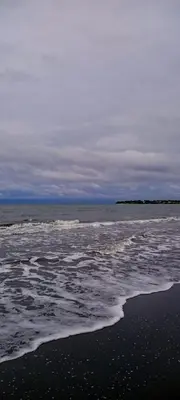 a beach with a body of water with waves at El Castillo in Moñitos