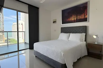 a bedroom with a white bed and a large window at Hermoso Apto de 1 hab con Vista al Mar - Piso 10 in Cartagena de Indias