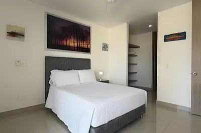 a bedroom with a white bed and a painting on the wall at Hermoso Apto de 1 hab con Vista al Mar - Piso 10 in Cartagena de Indias