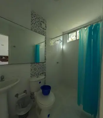 a bathroom with a toilet and a blue shower curtain at Hostel Casa Kanaloa Isla de Baru in Ararca
