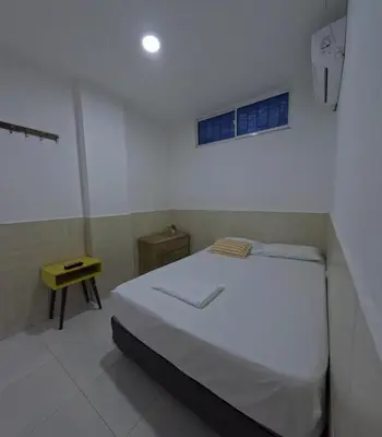 a bedroom with a white bed and a yellow table at Hostel Casa Kanaloa Isla de Baru in Ararca