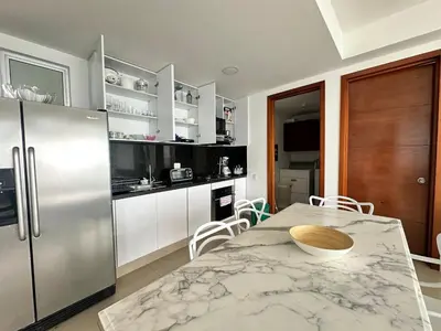 a kitchen with a table and a stainless steel refrigerator at 2BR apartment Ocean & old city view in Cartagena de Indias