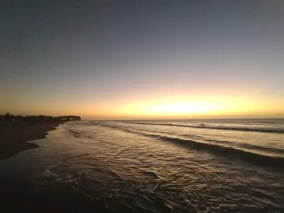 a beach with the sun setting on the water at Apartamento completo, serena del mar, Capriella in Cartagena de Indias
