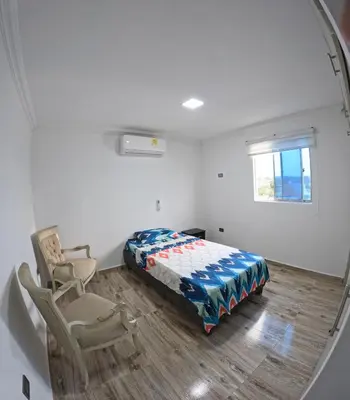 a bedroom with a bed and a chair and a window at Apartamento Mirador cerca al Centro Historico in Cartagena de Indias
