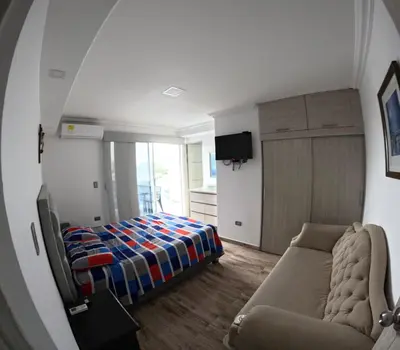 a bedroom with a bed and a couch and a mirror at Apartamento Mirador cerca al Centro Historico in Cartagena de Indias