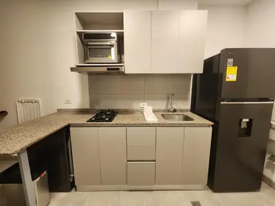 a kitchen with white cabinets and a black refrigerator at Apartamento vacacional con acceso al mar in Santa Marta