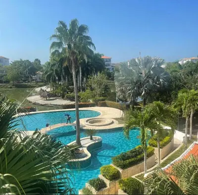 a swimming pool with palm trees in a resort at CONDOMINIO LAGUNA CLUB 