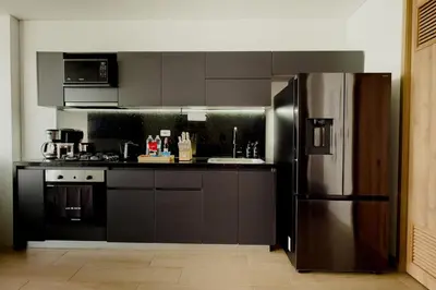 a kitchen with a stainless steel refrigerator and black cabinets at Now booking April! Walking to City Center 2 BDRM in Cartagena de Indias