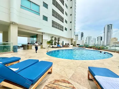 a pool in a building with blue lounge chairs at 2Br apartment in front of the beach in Cartagena de Indias