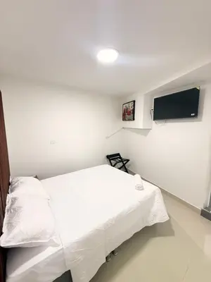 a bedroom with a white bed and a flat screen tv at Hotel CARTAGENA ES in Cartagena de Indias