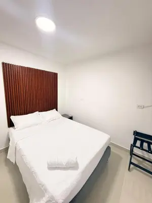 a bedroom with a white bed with a wooden headboard at Hotel CARTAGENA ES in Cartagena de Indias