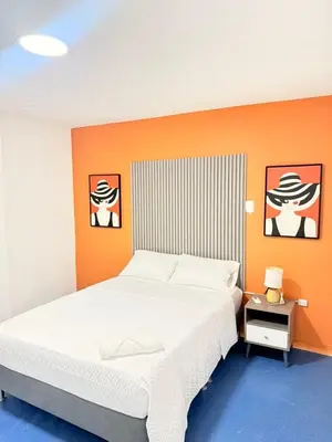 a bedroom with a white bed and an orange wall at Hotel CARTAGENA ES in Cartagena de Indias
