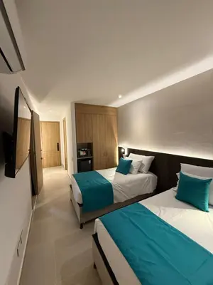 a hotel room with two beds and a television at Luxy 2BR at paradise Oasis, 18 min from walled city in Cartagena de Indias