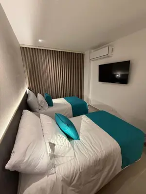 a hotel room with two beds with blue pillows at Luxy 2BR at paradise Oasis, 18 min from walled city in Cartagena de Indias