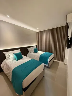 a hotel room with two beds with blue pillows at Luxy 2BR at paradise Oasis, 18 min from walled city in Cartagena de Indias